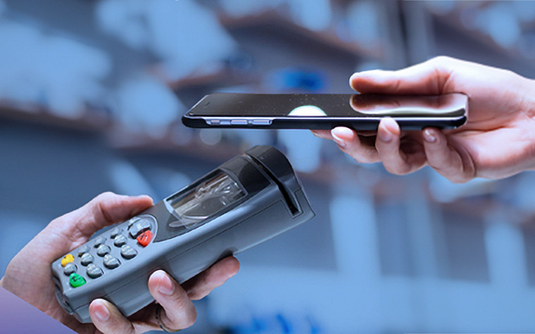 Nærbilde av to hender, den ene holder en kortmaskin og den andre en smarttelefon